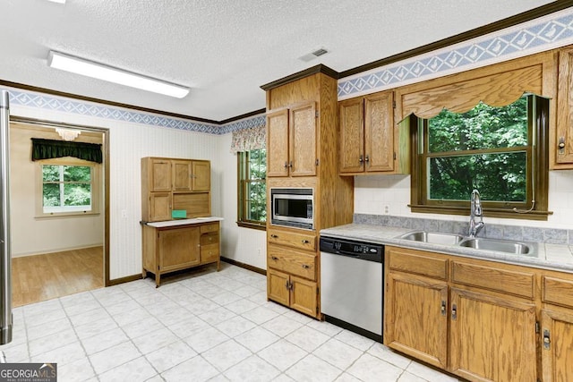 kitchen featuring a textured ceiling, stainless steel appliances, crown molding, and sink