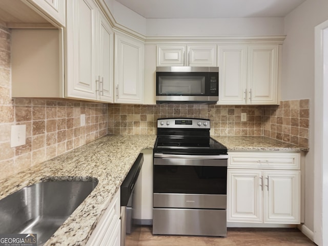 kitchen featuring decorative backsplash, stainless steel appliances, light stone counters, and wood-type flooring