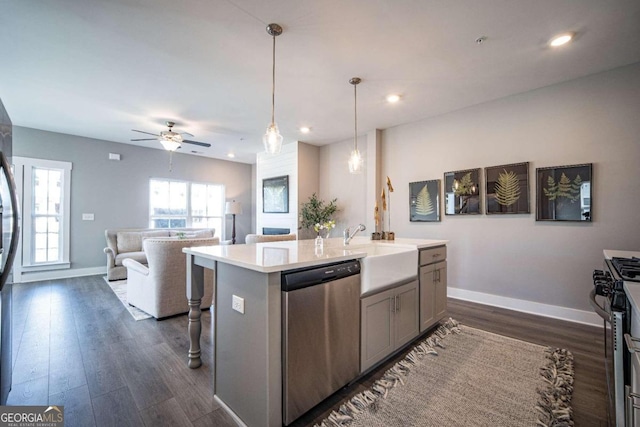 kitchen featuring pendant lighting, an island with sink, sink, dark hardwood / wood-style flooring, and stainless steel appliances