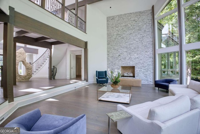 interior space featuring beam ceiling, a stone fireplace, a towering ceiling, and dark hardwood / wood-style floors