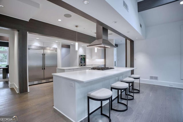 kitchen featuring white cabinets, hanging light fixtures, dark hardwood / wood-style floors, appliances with stainless steel finishes, and island exhaust hood