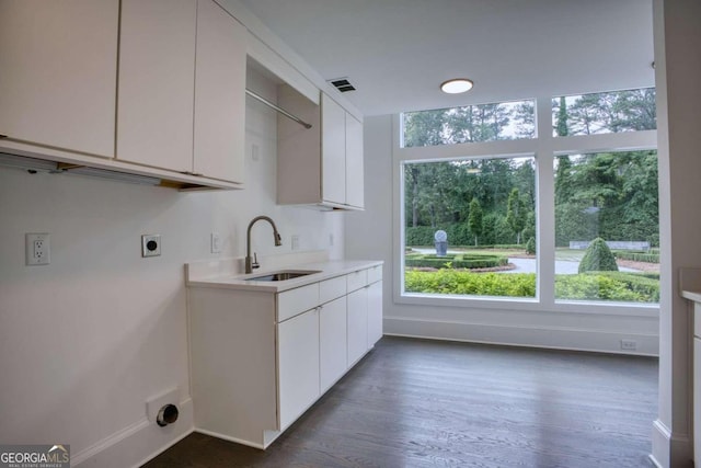 clothes washing area with electric dryer hookup, sink, cabinets, and dark hardwood / wood-style floors