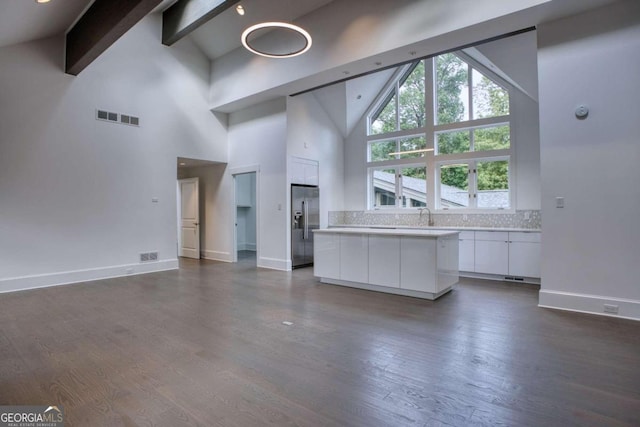 unfurnished living room featuring beam ceiling, high vaulted ceiling, and dark wood-type flooring