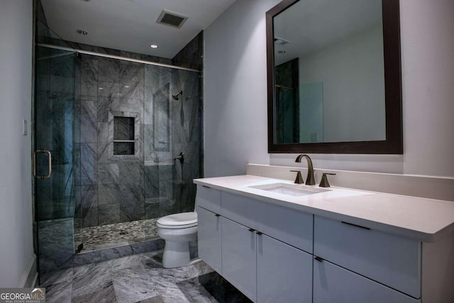 bathroom featuring vanity, a shower with shower door, and toilet