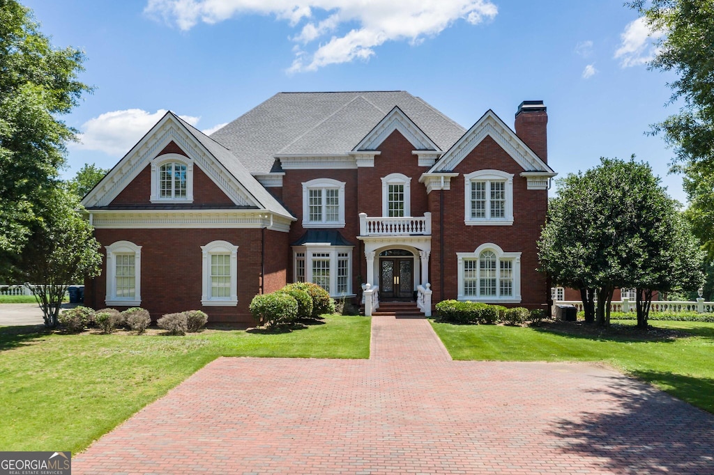 view of front of property featuring a front yard and a balcony