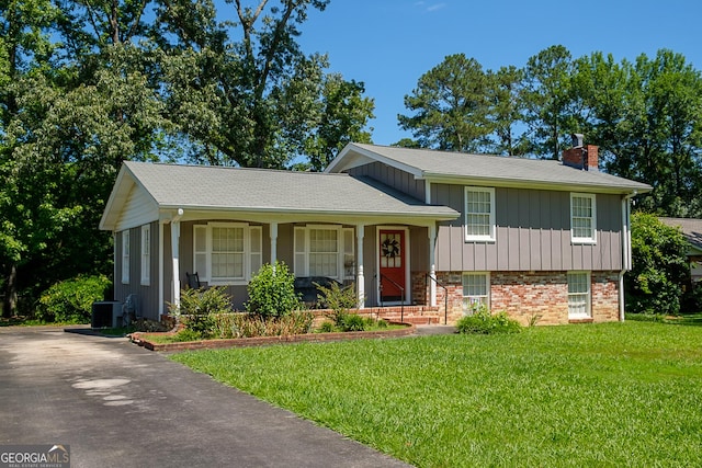 split level home with central AC unit and a front lawn