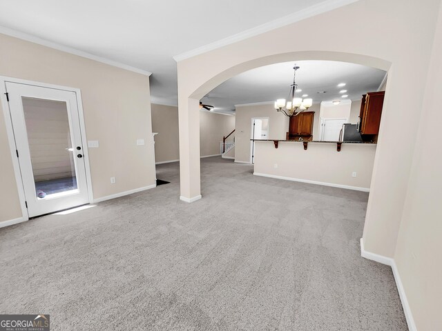 unfurnished living room with a notable chandelier, crown molding, and light carpet