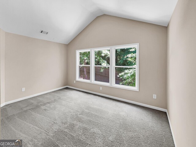 spare room with carpet flooring and vaulted ceiling