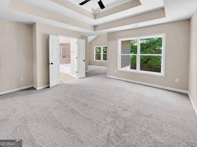 interior space featuring ceiling fan, light colored carpet, and a tray ceiling