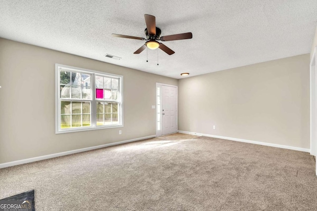 carpeted spare room featuring ceiling fan and a textured ceiling