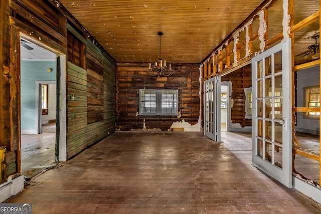 spare room with wood-type flooring, an inviting chandelier, wooden walls, and wood ceiling