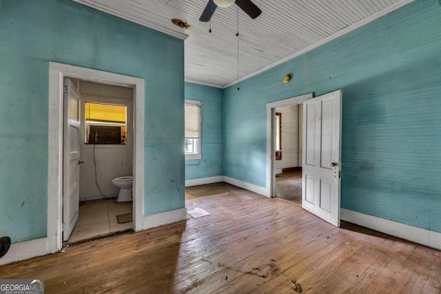 unfurnished bedroom with hardwood / wood-style floors, ceiling fan, cooling unit, and ensuite bathroom