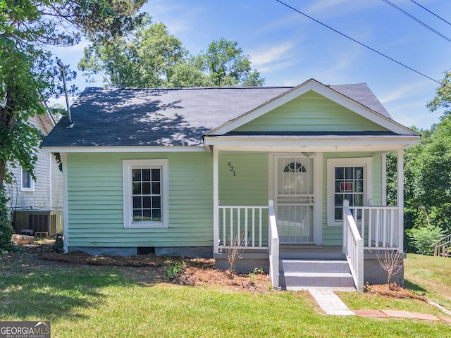 bungalow with central air condition unit, covered porch, and a front yard