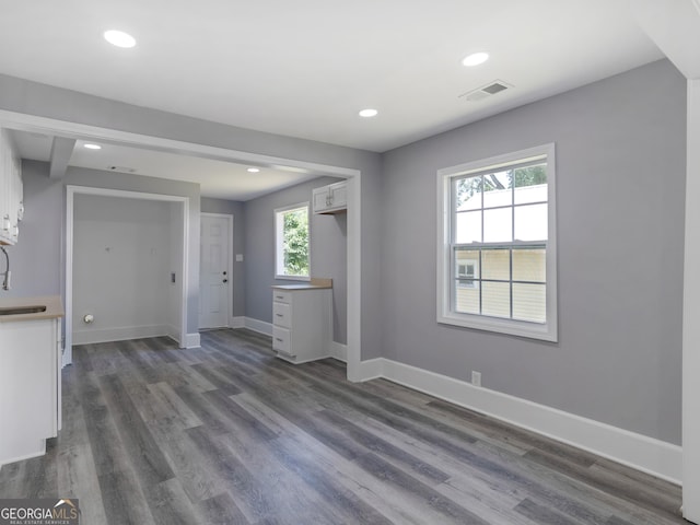 unfurnished living room with a wealth of natural light, dark wood-type flooring, and sink