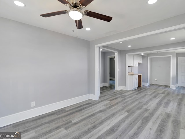 unfurnished living room with light wood-type flooring, ceiling fan, and sink