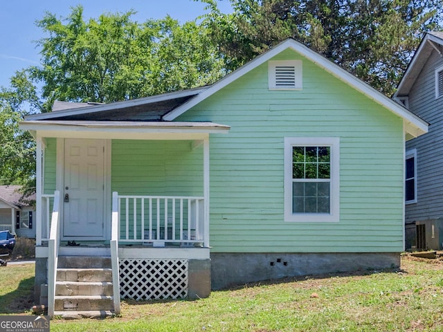 view of front of property with a front lawn, covered porch, and central AC unit