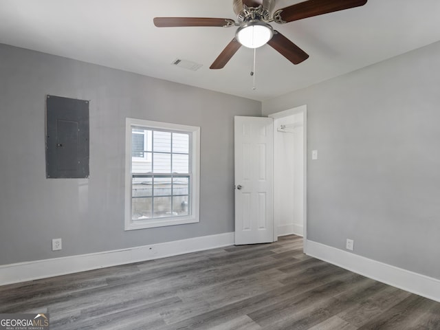 empty room with ceiling fan, dark hardwood / wood-style floors, and electric panel