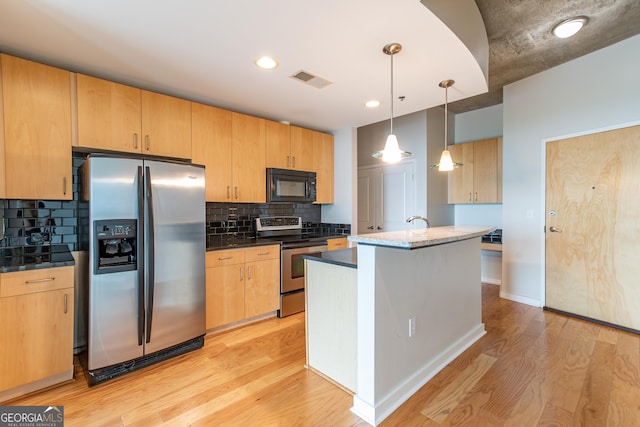 kitchen with appliances with stainless steel finishes, tasteful backsplash, light brown cabinetry, hanging light fixtures, and light hardwood / wood-style flooring