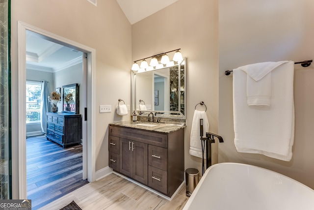 bathroom with crown molding, a washtub, and vanity