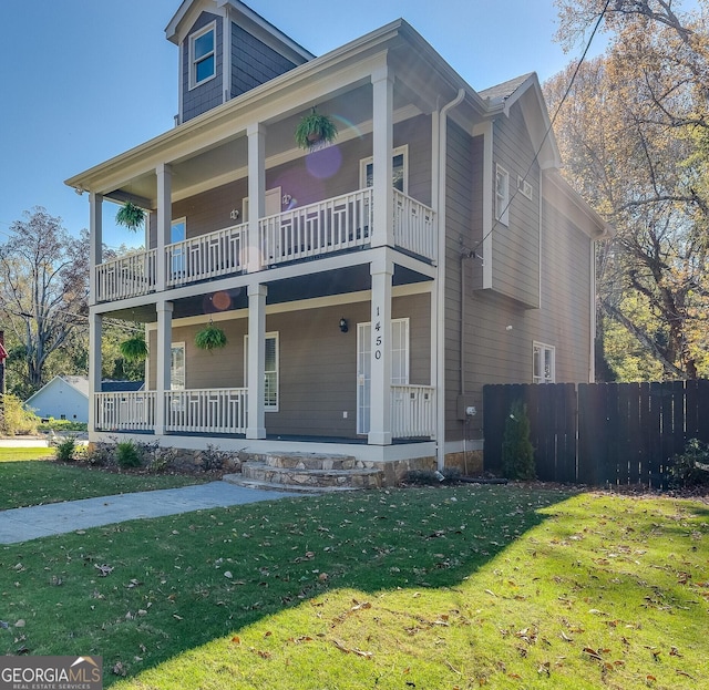 view of front of property with covered porch, a balcony, and a front lawn