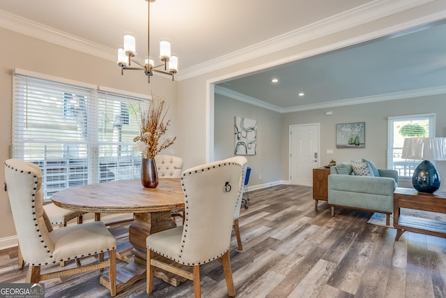 dining room featuring hardwood / wood-style floors, a healthy amount of sunlight, crown molding, and a chandelier