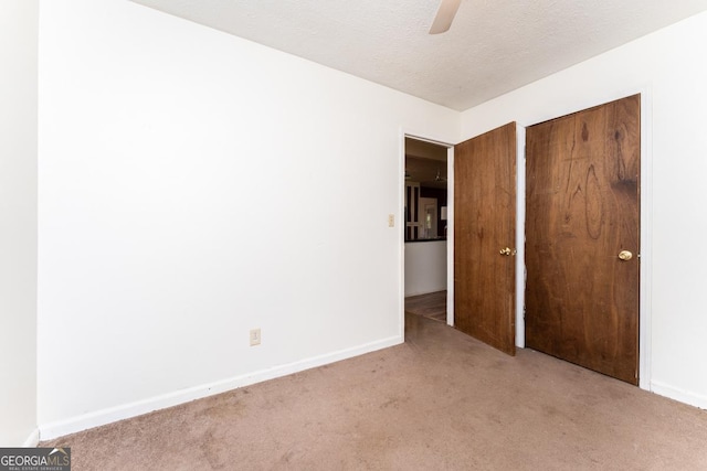 unfurnished bedroom with ceiling fan, a closet, a textured ceiling, and carpet flooring