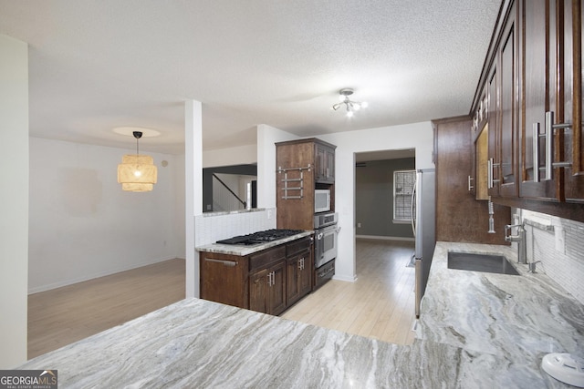 kitchen featuring appliances with stainless steel finishes, decorative light fixtures, dark brown cabinets, and sink