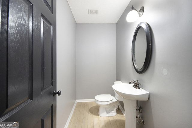 bathroom with hardwood / wood-style flooring, toilet, and sink