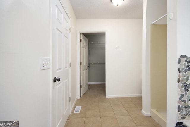 hall with light tile patterned floors and a textured ceiling