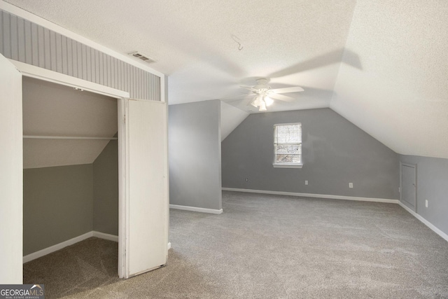 additional living space featuring ceiling fan, carpet floors, a textured ceiling, and lofted ceiling