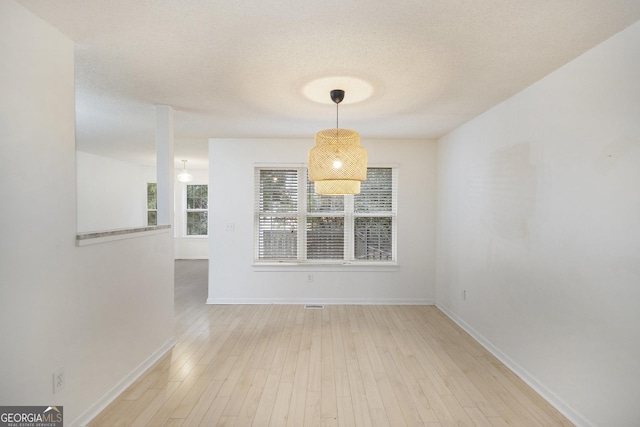 unfurnished dining area with hardwood / wood-style floors and a textured ceiling