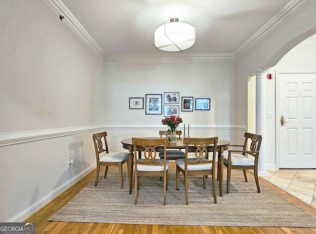 dining room featuring ornate columns, hardwood / wood-style floors, and crown molding