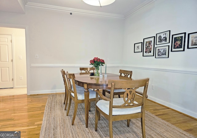 dining room with ornamental molding and light hardwood / wood-style floors