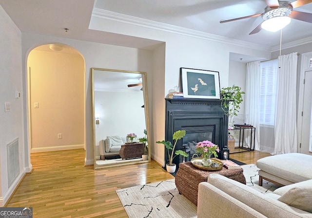 living room featuring ceiling fan, ornamental molding, and light hardwood / wood-style floors