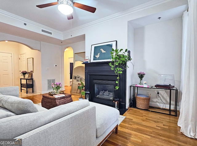 living room featuring crown molding, wood-type flooring, and ceiling fan