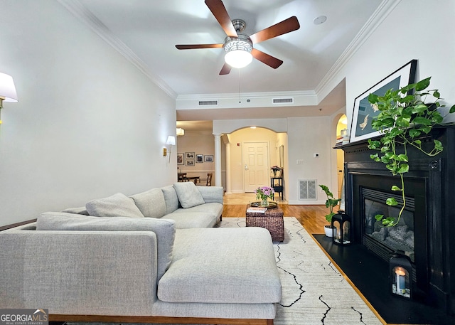 living room featuring wood-type flooring, ceiling fan, and crown molding