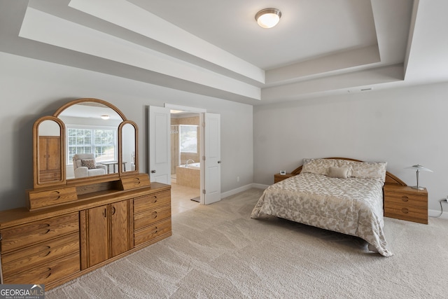 carpeted bedroom with a tray ceiling and ensuite bathroom