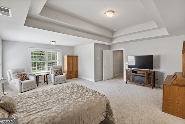 bedroom with light colored carpet and a tray ceiling