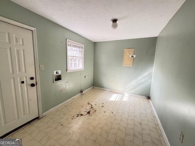 clothes washing area featuring electric panel, hookup for a washing machine, and a textured ceiling