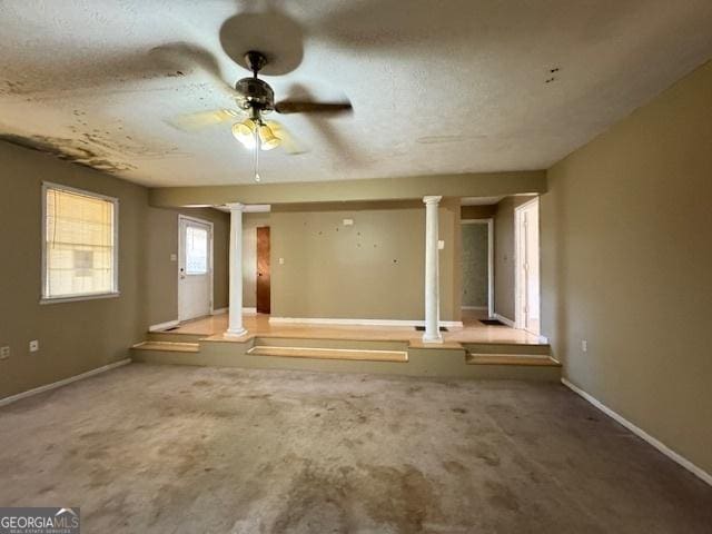 spare room featuring carpet floors, ceiling fan, and ornate columns