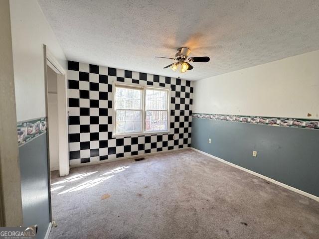 carpeted spare room with ceiling fan and a textured ceiling