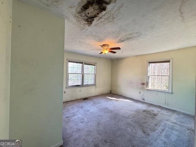 carpeted empty room featuring ceiling fan and a textured ceiling