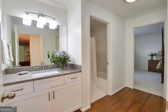 bathroom featuring hardwood / wood-style floors, ornamental molding, and a textured ceiling