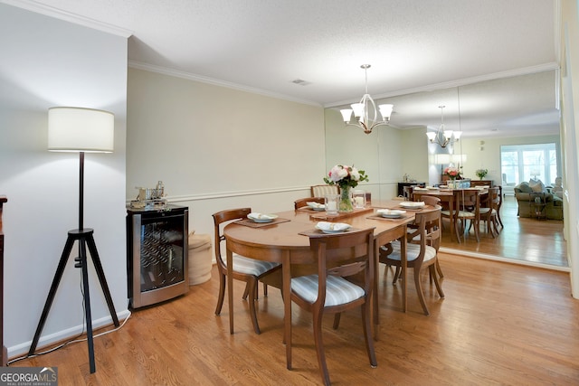 dining space with wine cooler, crown molding, light hardwood / wood-style flooring, and a notable chandelier