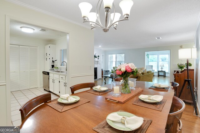 tiled dining room featuring sink, an inviting chandelier, and ornamental molding