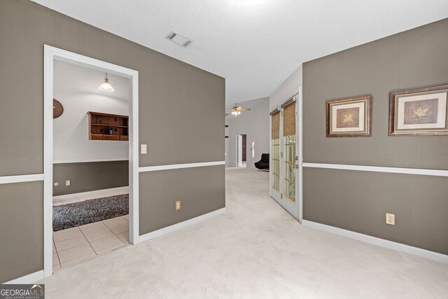 spare room with a textured ceiling, ceiling fan, and light carpet