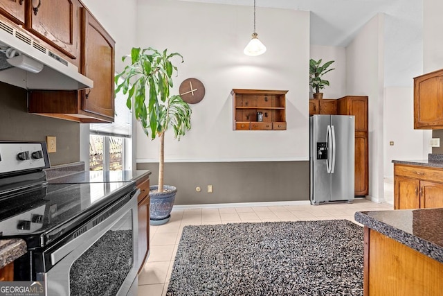 kitchen with light tile patterned floors, decorative light fixtures, stainless steel appliances, and a high ceiling