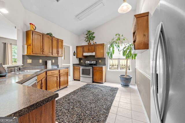 kitchen featuring appliances with stainless steel finishes, vaulted ceiling, sink, and light tile patterned flooring