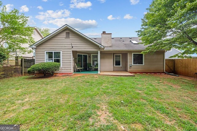 back of house with a lawn and a patio