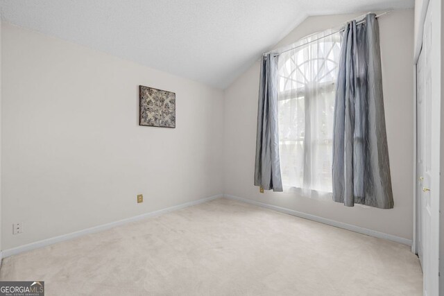 carpeted spare room with vaulted ceiling and a wealth of natural light